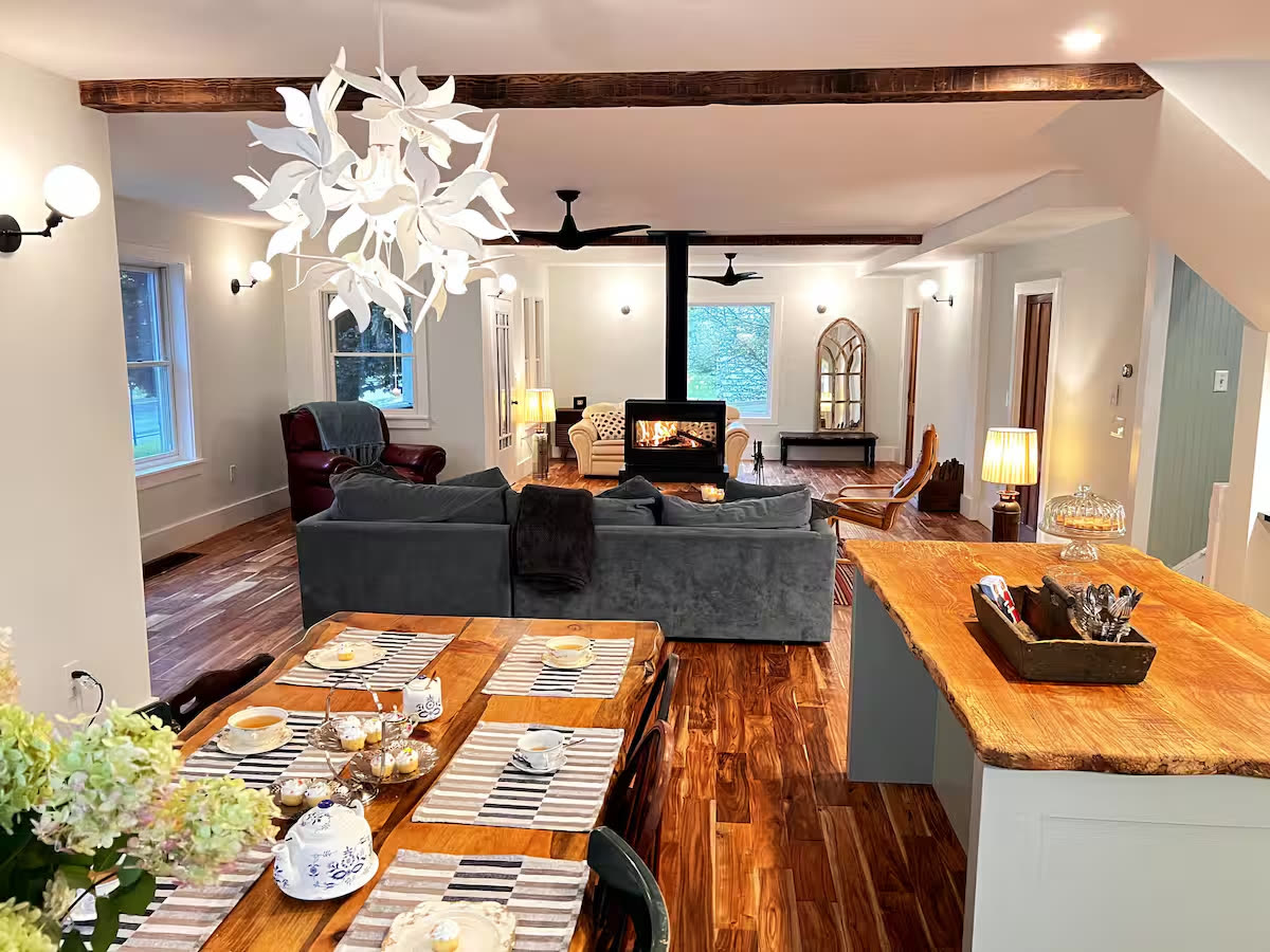 Open living and dining room with a wood stove, live-edge kitchen island and long farmhouse table